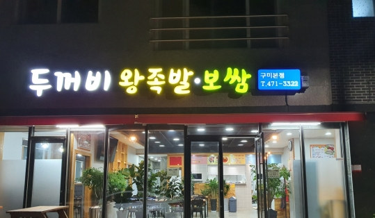 밤의 가게 외관 — 불 켜진 간판 ‘두꺼비 왕족발·보쌈 구미본점 T.471-3322’과 유리 입구