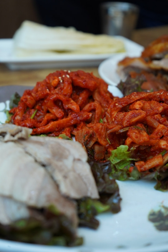 보쌈에 곁들이는 무김치 접사, 앞에 수육, 뒤에 백김치와 족발 접시